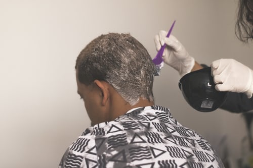 Hairdresser applying hair dye to client's hair