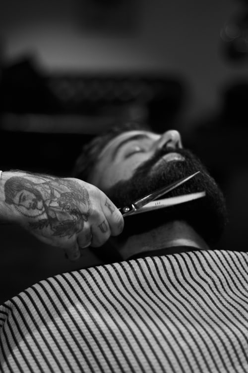 Barber using scissors to trim client's beard