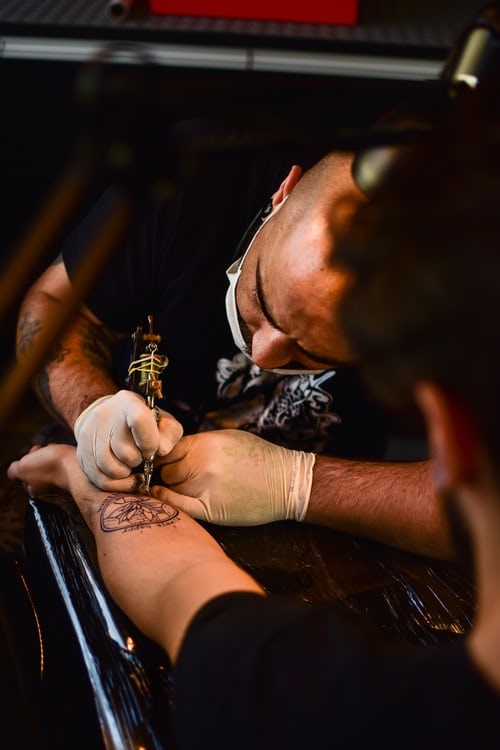 Tattoo artist tattooing a client's arm