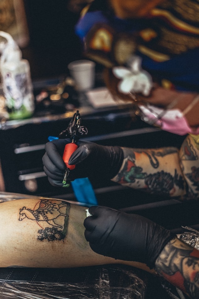 Tattoo artist tattooing a client's leg