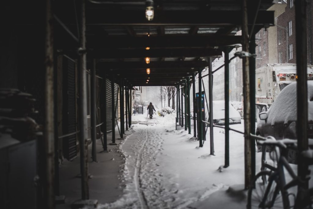 City sidewalk under scaffolding during a snowstorm
