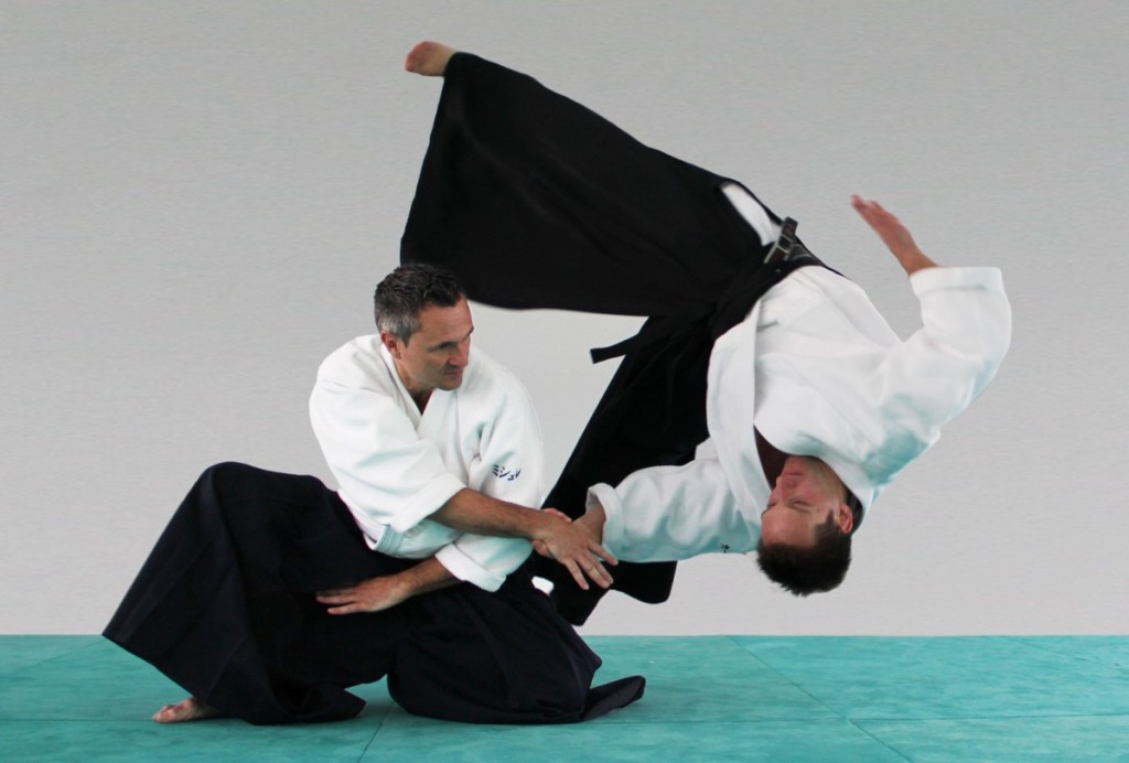 Aikido instructor performing a takedown move on a partner
