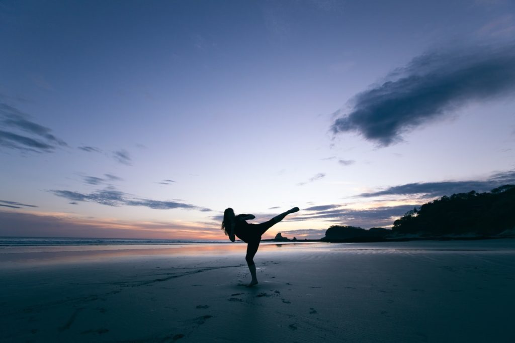 Silhouette of karate instructor kicking while on a beach