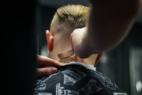 Hairdresser shaving the back of client's neck
