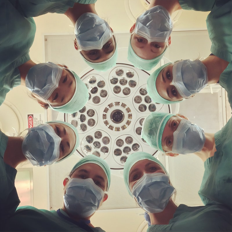Medical students standing over a patient looking down