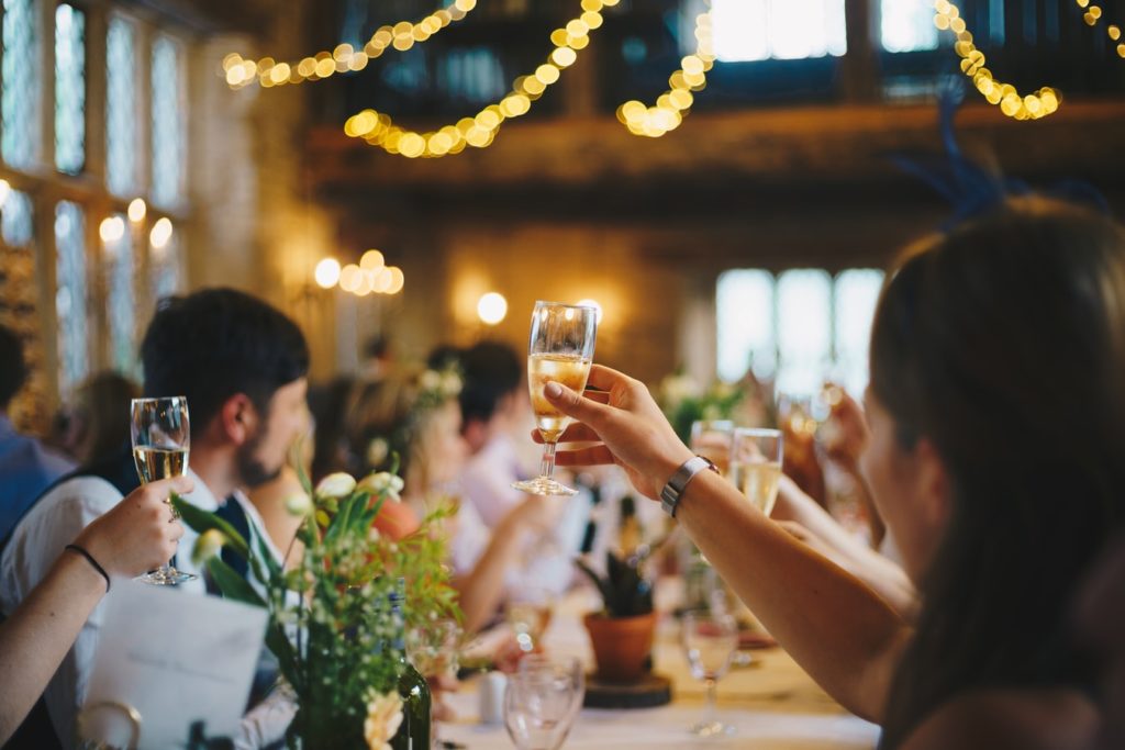 Guests at a wedding raising their glasses during a toast