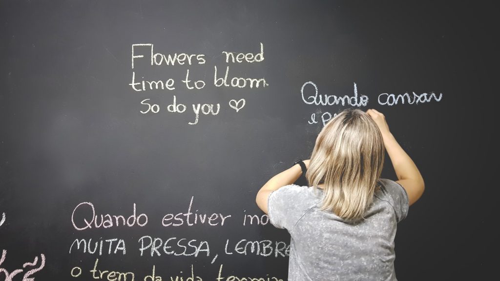 Language tutor writing out an English phrase in another language on a chalkboard