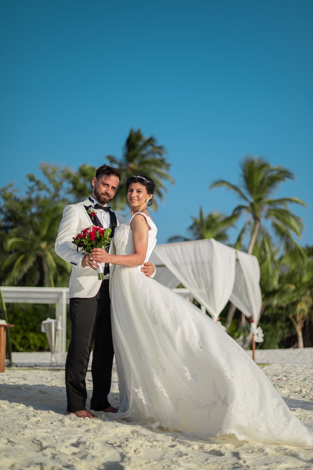 Newlyweds posing together on a beach