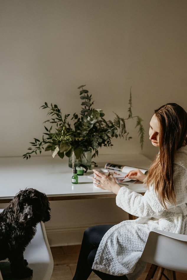 Pet sitter reading a magazine at the kitchen table while watching a dog