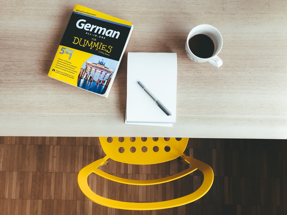 Overhead image of a desk with coffee, notepad and a German for Dummies book