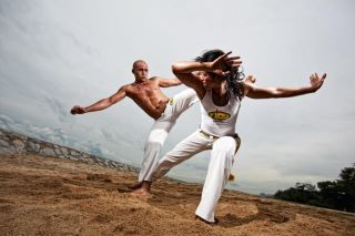 Capoeira instructors sparring on a beach
