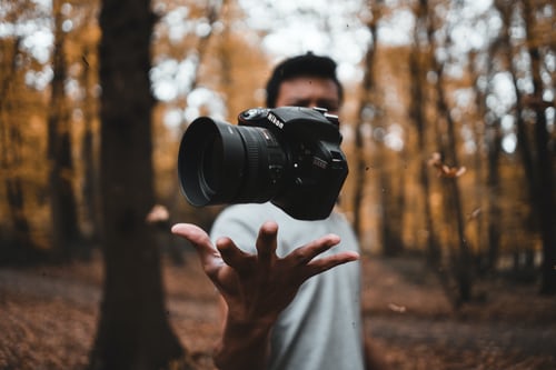 Freelance photographer tossing a camera with his hand