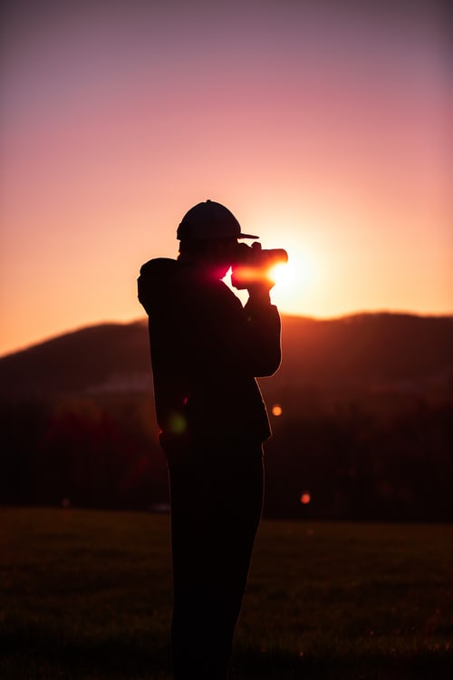 Silhouette of a landscape photographer capturing a sunset