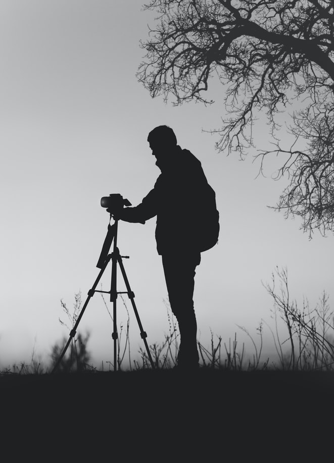 Silhouette of a wildlife photographer setting up a tripod